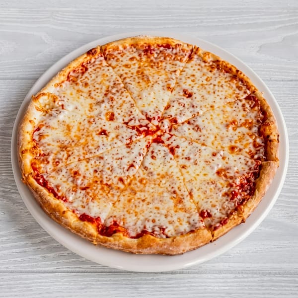 A whole cheese pizza, cut into eight slices, on a white plate against a light wooden table.