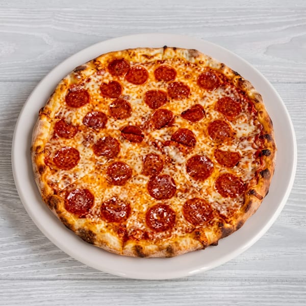 A whole pepperoni pizza with melted cheese on a white plate, viewed from directly above.